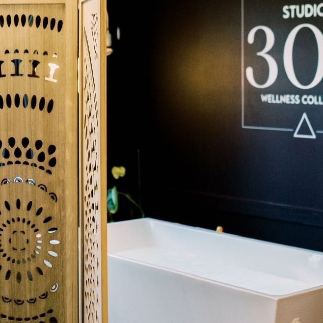 The cold plunge tub beside a carved wooden screen
